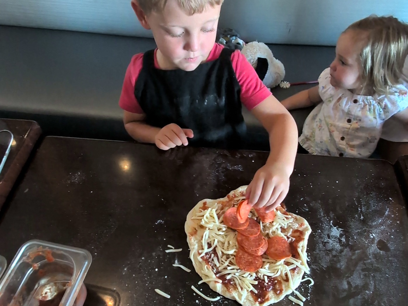 Child adding toppings to a personal pizza during a hands-on Ruckus class.