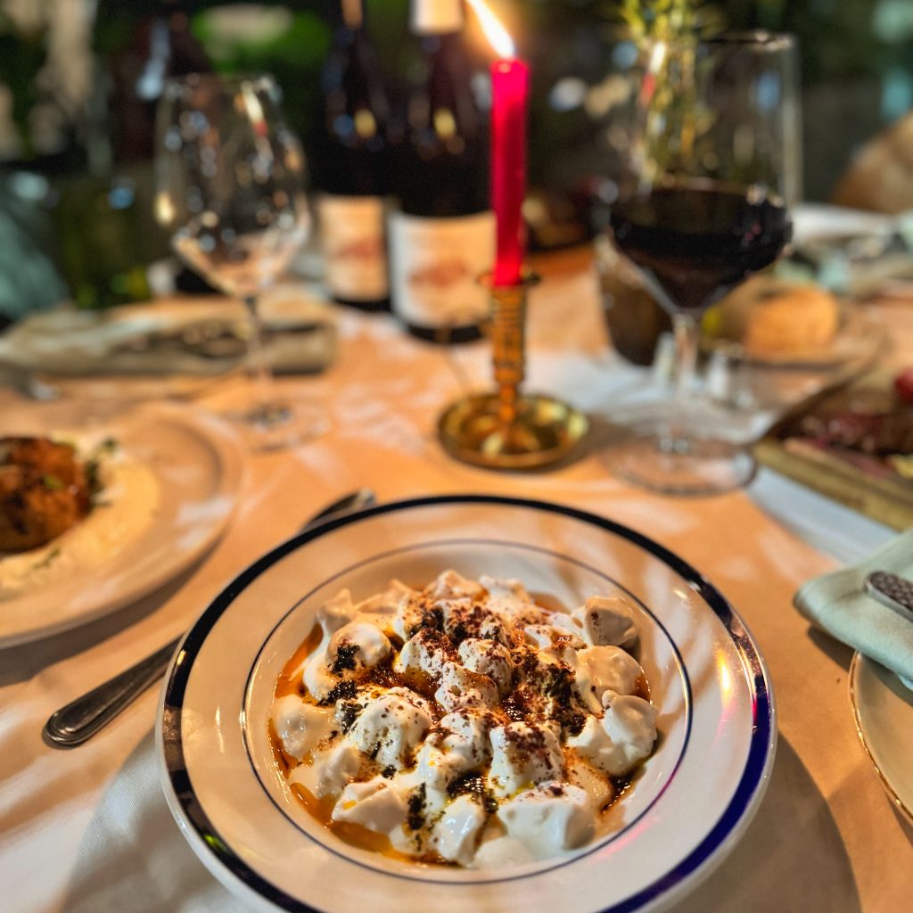 A plate of traditional Turkish homemade manti served with garlic yogurt and spiced butter sauce at Jass Kitchen Miami