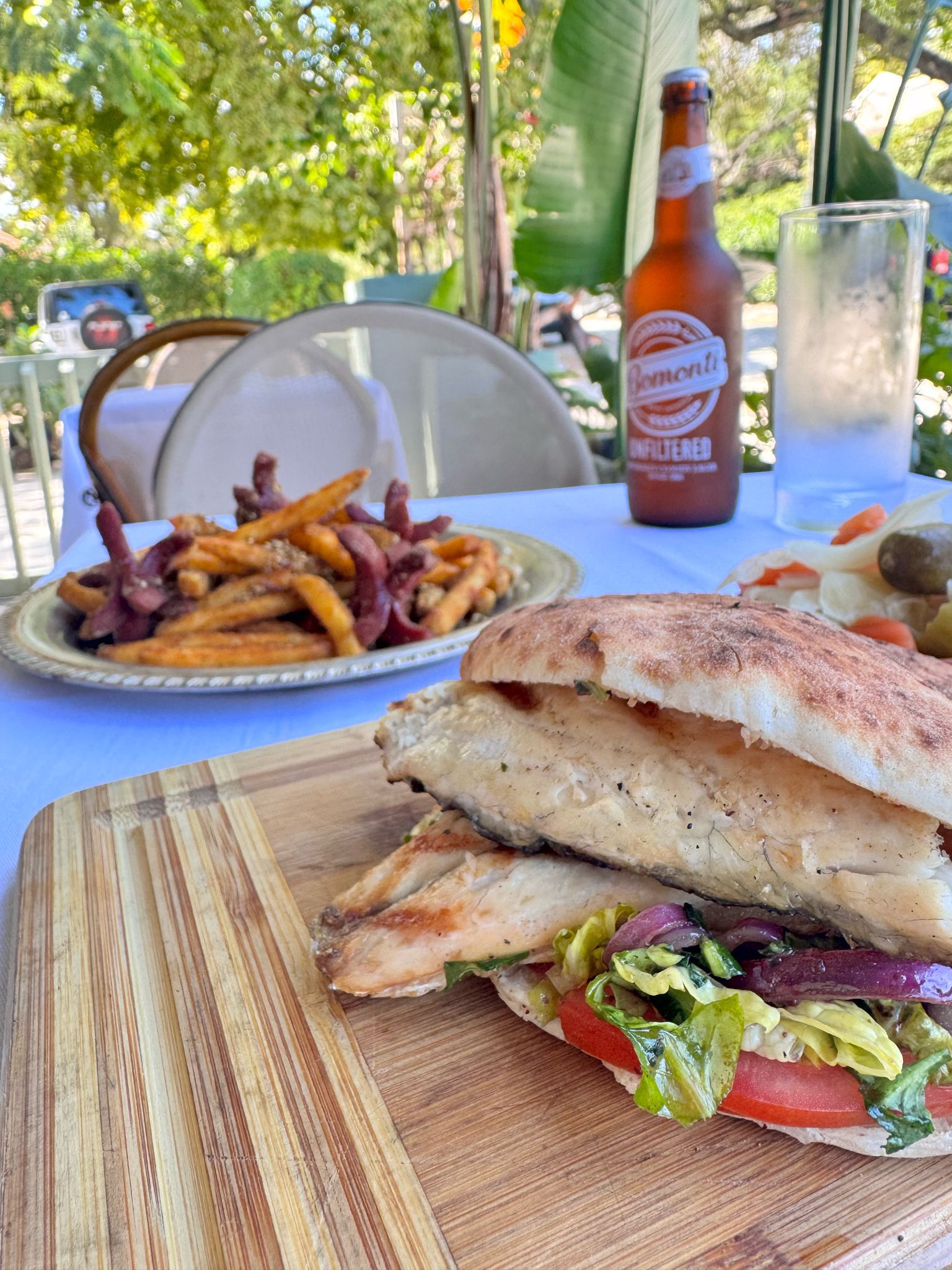 Eminonu fish sandwich with grilled Branzino, lettuce, tomato, and onions served at Jass Kitchen, the best lunch restaurant in Miami, with fries and cold beer.