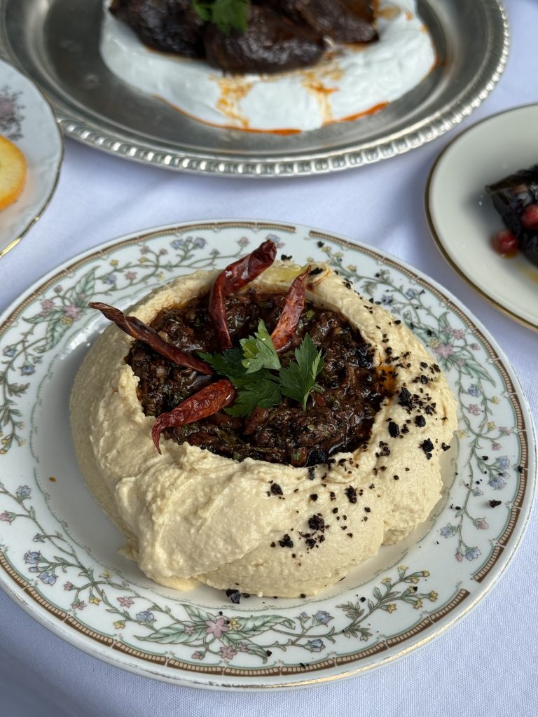 Creamy hummus topped with herbs and chili oil served at a Mediterranean restaurant Miami.