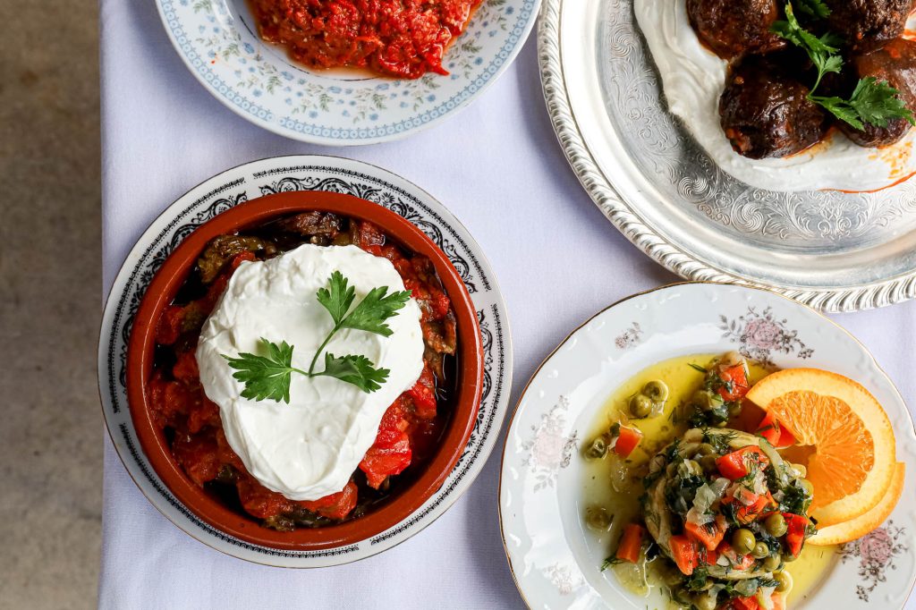 A selection of Mediterranean mezze dishes—including yogurt-topped warm appetizer, spicy dip, and fresh salad—served at a Mediterranean restaurant Miami.
