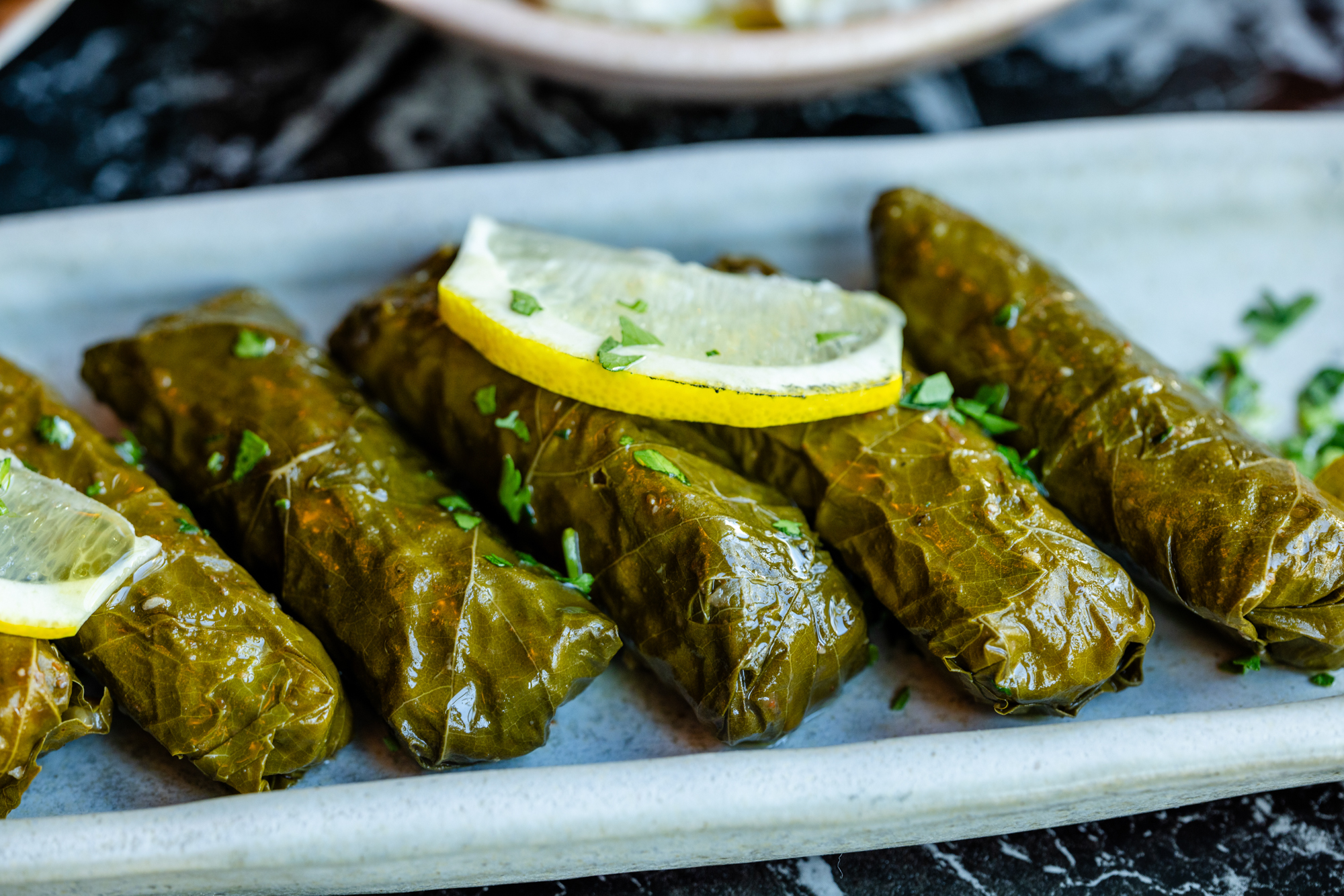 A step-by-step preparation of stuffed grape leaves showing ingredients and rolling technique — perfect for anyone learning how to make grape leaves at home.