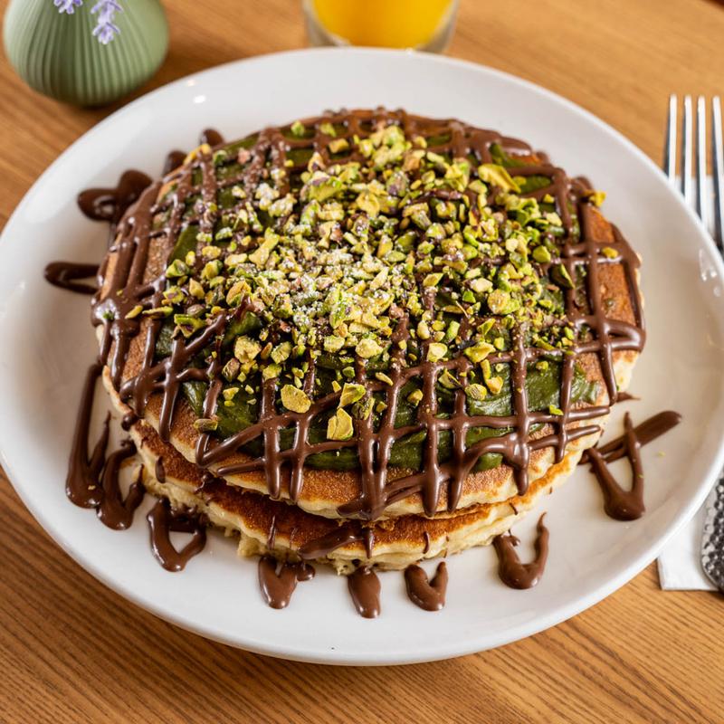 Nutella and pistachio pancakes topped with crushed pistachios and chocolate drizzle at 5800 North Cafe
