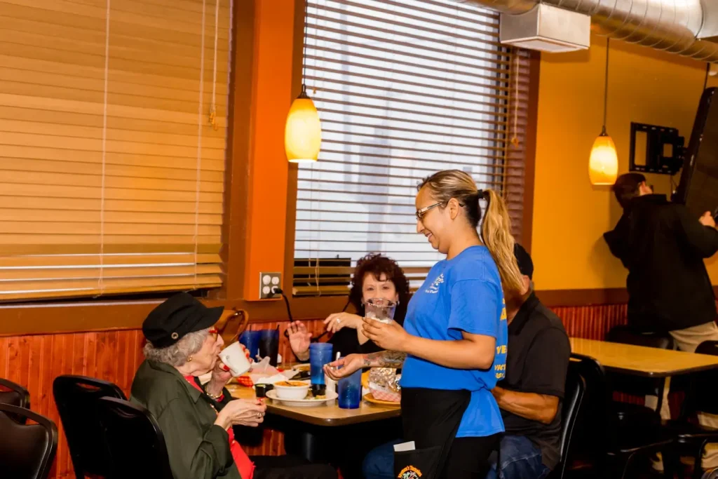 Waitress serving customers in restaurant.
