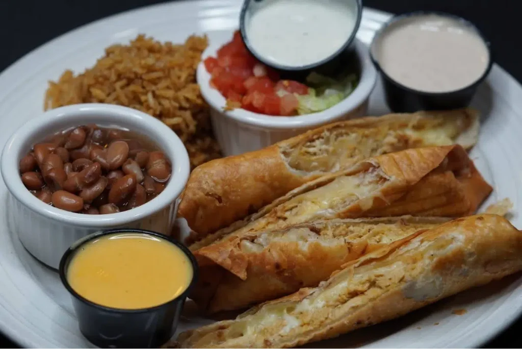 Crispy chicken flautas with rice, beans, and dipping sauces.