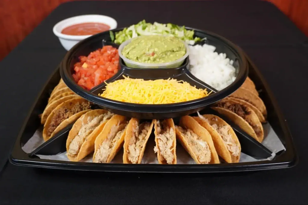 Taco platter with assorted beef and chicken tacos, served with sides of guacamole.