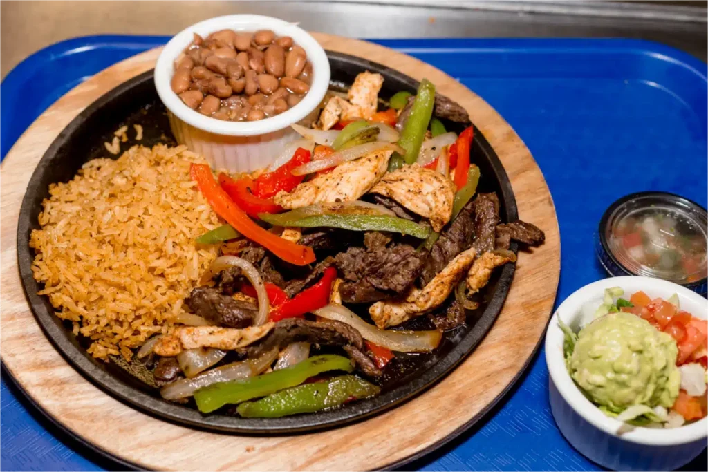 A sizzling platter of chicken and beef fajitas with sautéed bell peppers and onions.